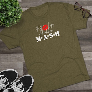 May include: Olive green t-shirt with white text that reads "Hot Lips Houlihan M*A*S*H" with a red lip print.
