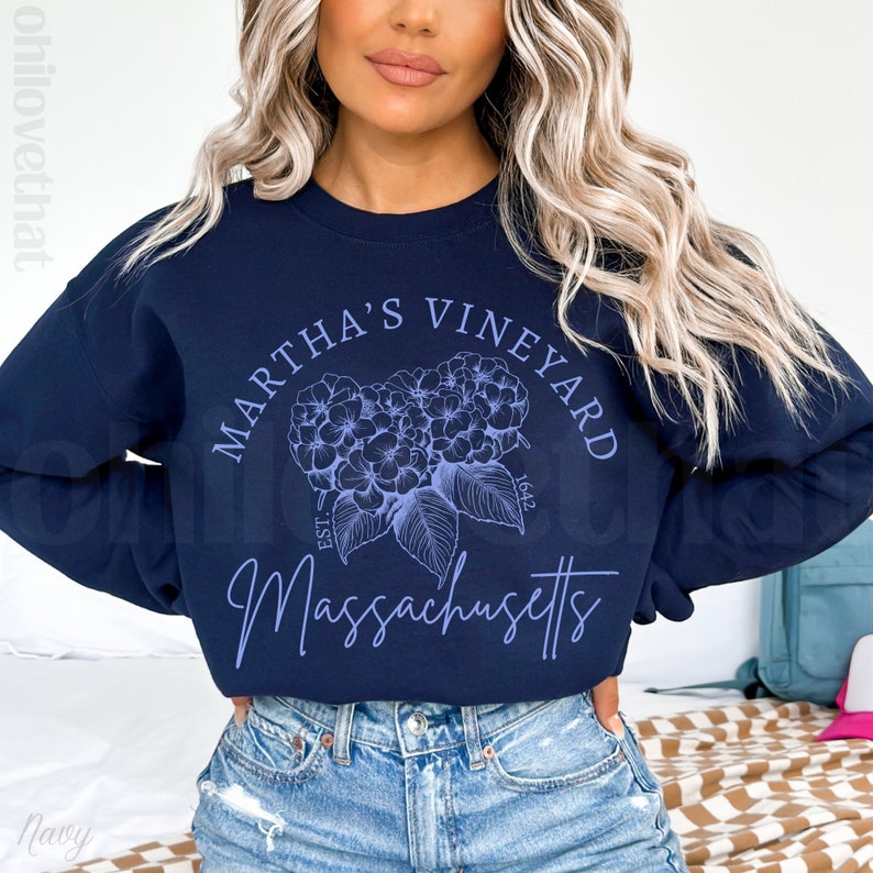 May include: A navy blue sweatshirt with a white graphic design that says "Martha's Vineyard Est. 1642 Massachusetts". The graphic also features a blue floral design.