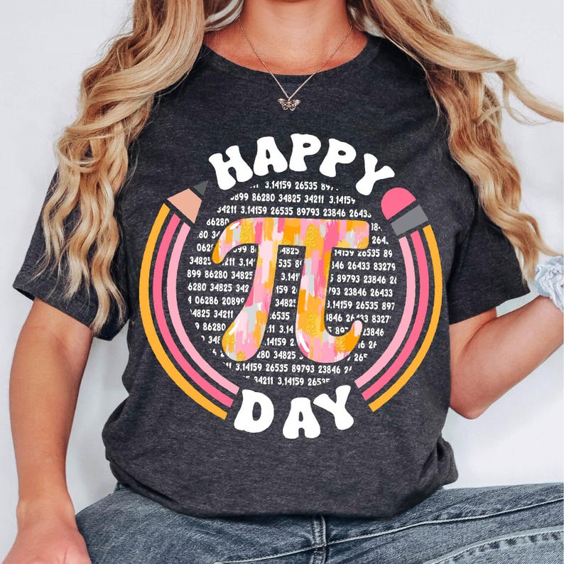 May include: A dark grey t-shirt with a colorful graphic design featuring the mathematical constant pi. The graphic includes the text "Happy Pi Day" and a rainbow of colors.