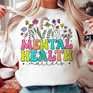 May include: White sweatshirt with a colorful floral design and the text "Mental Health matters".