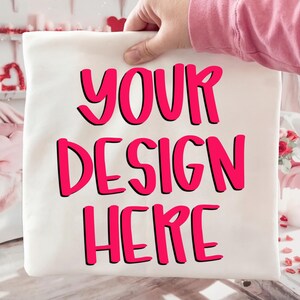 May include: A white pillowcase with the words "YOUR DESIGN HERE" in bright pink, outlined in black. The text is centered on the pillowcase. The pillowcase is being held up by a person.