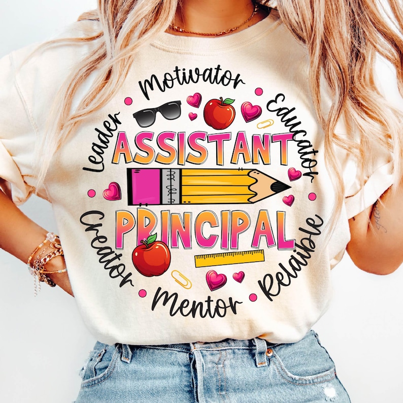 May include: A white t-shirt with a pink and yellow graphic design that says 'Assistant Principal' with other words around it including 'Motivator', 'Leader', 'Creator', 'Mentor', 'Educator', 'Reliable'.