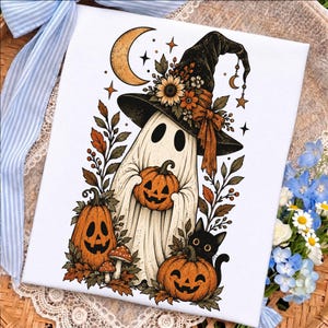 May include: A white canvas print featuring a central ghost wearing a black witch hat adorned with sunflowers and orange ribbons. The ghost holds a jack-o'-lantern, with two additional jack-o'-lanterns, a black cat, mushrooms, and autumn leaves.