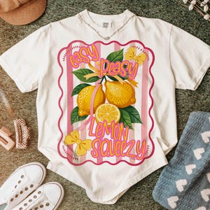 Peut inclure: T-shirt blanc avec un motif ray&eacute; rose et blanc repr&eacute;sentant des citrons et le texte "easy peasy lemon squeezy".