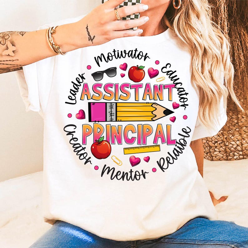 May include: White t-shirt with a colorful graphic design for an assistant principal. The design includes a pencil, apple, sunglasses, and the words "Motivator, Leader, Creator, Mentor, Reliable, Educator." The word "Assistant Principal" is prominently displayed.