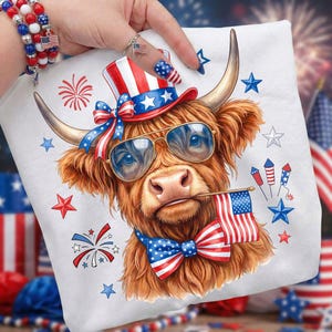 May include: White pillow featuring a Highland cow wearing sunglasses, a patriotic hat, and a bow tie, holding a small American flag in its mouth. The design incorporates red, white, and blue stars and stripes, with fireworks and star accents.