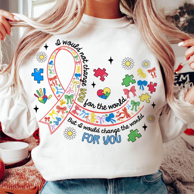May include: White sweatshirt with a colorful ribbon and puzzle pieces. The text reads "I would not change you for the world, but I would change the world for you."