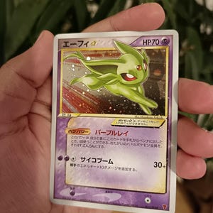 Puede incluir: Una carta coleccionable Pokémon japonesa Espeon Star con acabado holográfico. La carta presenta una ilustración de un Espeon verde, 70 HP y texto que incluye "エーフィ" y "サイコブーム". La carta tiene un borde morado y texto en japonés.