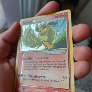 May include: A Flareon Star trading card with 70 HP, featuring a holographic illustration of the fire-type creature. The card displays the Crimson Ray Poke-Power and Flamethrower attack, with a red border, 2007 copyright, and 100/108 numbering.