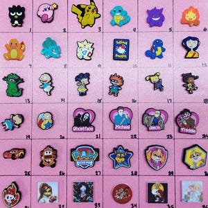 May include: A collection of 36 colorful cartoon character shoe charms. The charms feature characters from popular cartoons, movies, and video games, including Pokemon, Rugrats, Paw Patrol, and more.