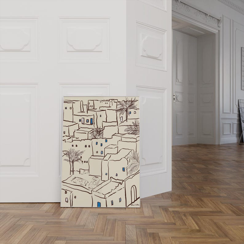 Pu&ograve; includere: Una stampa artistica raffigurante un paesaggio urbano stilizzato con edifici beige, contorni neri e accenti di finestre blu. Anche le palme sono incluse nell'illustrazione. L'opera d'arte &egrave; esposta su un muro bianco.