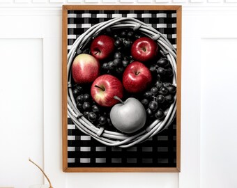 Op de afbeelding: Een rieten mand gevuld met rode appels en druiven. De mand staat op een zwart-wit geblokte achtergrond.