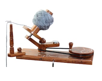 May include: A wooden yarn swift with a grey ball of yarn on the spindle. The swift has a crank handle and a wooden base.