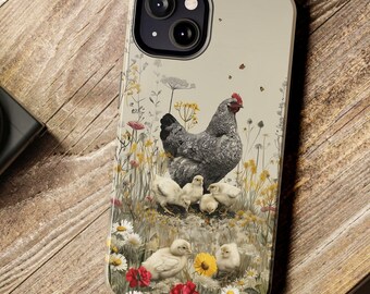 May include: A phone case featuring a hen with her chicks in a field of wildflowers. The case has a light beige background with a detailed illustration of the hen, chicks, and colorful flowers. The case is on a wooden surface.