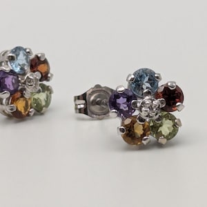 May include: A pair of silver flower-shaped earrings with a variety of gemstones, including amethyst, topaz, citrine, and garnet.