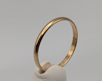 May include: A simple gold band ring.