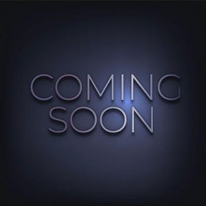 May include: A dark blue background with the words "COMING SOON" in a silver, sans-serif font. The text is slightly raised, creating a subtle shadow effect. The overall design is simple and modern.