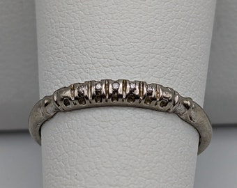 May include: A thin silver band with a row of small diamonds set in the center.