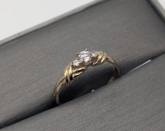 May include: A gold ring with three small diamonds set in a twisted band.