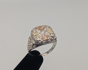Puede incluir: Un anillo de plata con un engaste cuadrado que presenta un diseño floral en oro, verde y rojo.