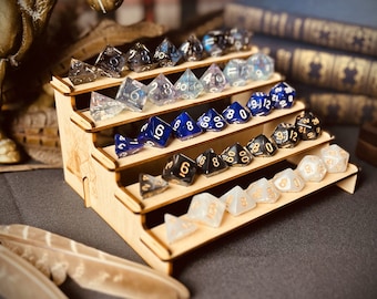 May include: A wooden tiered display stand with five shelves, showcasing a collection of colorful dice. The dice are made of various materials, including clear, blue, black, and white. The stand is perfect for displaying and organizing dice for tabletop games.