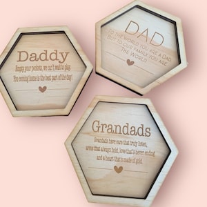 May include: Three hexagonal wooden coasters with engraved messages. The coasters feature the words "Daddy", "Dad", and "Grandads" with corresponding messages about family and love.