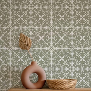 May include: A terracotta-colored vase with a circular opening, a dried palm leaf, and a woven basket sit on a wooden surface. The background features a sage green wallpaper with a white, repeating floral pattern, creating a serene, decorative scene.