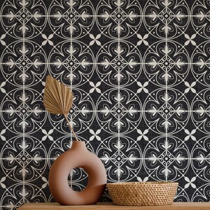 May include: A decorative arrangement featuring a dark background with a white geometric pattern. A terracotta-colored vase with a circular opening holds a dried palm leaf. A woven basket sits nearby, creating a stylish, neutral-toned display.