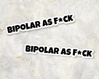 May include: Two white stickers with black text that reads "BIPOLAR AS F*CK" on a white fluffy surface.