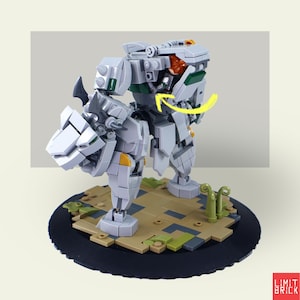 Może przedstawiać: Jasnoszary i biały model robota mech zbudowany z klock&oacute;w. Robot stoi na okrągłej czarnej podstawie z brązowo-zielonym terenem. Model ma przeguby i szczeg&oacute;łowy design z pomarańczowymi i zielonymi akcentami.