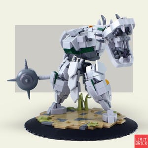 Może przedstawiać: Biało-szara figurka robota z cegieł z zielonymi i ż&oacute;łtymi akcentami, ustawiona na okrągłej czarnej podstawie. Robot ma dużą głowę z otwartymi ustami i kolczastą kulę przymocowaną z boku. Podstawa ma brązowo-zielony krajobraz.