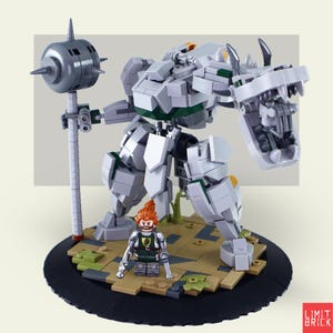 Może przedstawiać: Duży, przegubowy robot zbudowany z szarych i białych klock&oacute;w, trzymający szarą maczugę. Mała minifigurka z pomarańczowymi włosami i zielono-srebrnym strojem stoi przed robotem. Podstawa jest czarna z brązowymi i zielonymi akcentami.