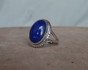 May include: A silver ring with a large oval lapis lazuli gemstone. The ring has a textured band and a simple design.