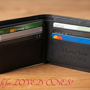 May include: Black leather wallet, open to display credit cards and a personalized message. The wallet has multiple card slots and a bill compartment. The text "I Love You 12-23-2021" is engraved on the inside.