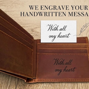 May include: Open brown leather wallet with multiple card slots. The text "WE ENGRAVE YOUR HANDWRITTEN MESSAGE" is at the top. A card with "With all my heart" is placed inside the wallet, and the same phrase is engraved on the wallet.