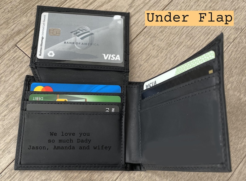 May include: Black leather wallet with multiple card slots, holding various credit and debit cards. The wallet is open, revealing the interior with the text "We love you so much Dady Jason, Amanda and wifey". The text "Under Flap" is also visible.