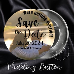 May include: A gold round button with a photo of a couple in a park. The text on the button reads "Save the Date July 20.2024 Denise & Anthony" and "We're getting married!"