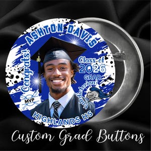 May include: A round, silver button with a photo of a smiling graduate wearing a cap and gown. The button has blue and white accents with the text "ASHTON DAVIS", "Class of 2026", "HIGHLANDS HS", and "Custom Grad Buttons".