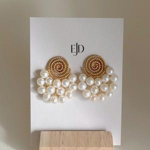 以下が含まれることがあります： 手作りの、クリーム色の斑点のある釉薬が施されたセラミックマグ。マグは幅広で丸みを帯びたボディと頑丈なハンドルが特徴です。内側はより暗く、アースカラーです。温かい飲み物にも冷たい飲み物にも適しています。