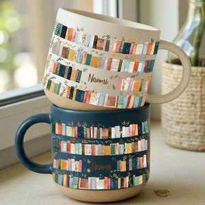 Może przedstawiać: Dwa ceramiczne kubki ułożone jeden na drugim. Górny kubek jest w kolorze złamanej bieli z beżowym uchwytem i podstawą, a dolny kubek jest granatowy. Oba kubki mają kolorowy wzór półki na książki z nadrukiem "Naomi".