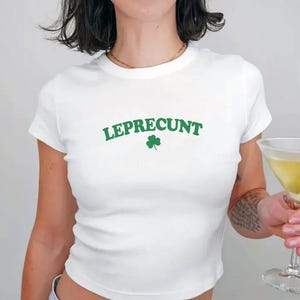 May include: White cropped t-shirt with the text "LEPRECUnt" in green letters and a green shamrock.