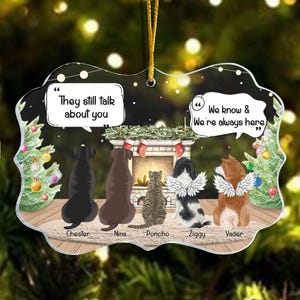 May include: A Christmas bauble with a white background and a fireplace scene. The bauble features five dogs, four of them with names: Chester, Nina, Poncho, Ziggy, and Vader. The text on the bauble reads "They still talk about you" and "We know & We're always here."