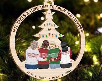 Può includere: Un ornamento di Natale in legno con un albero di Natale e quattro donne in piedi di fronte ad esso. L'ornamento recita "Ci vuole molto tempo per diventare vecchi amici". I nomi delle donne sono Teresa, Nicole, Maria e Olivia.
