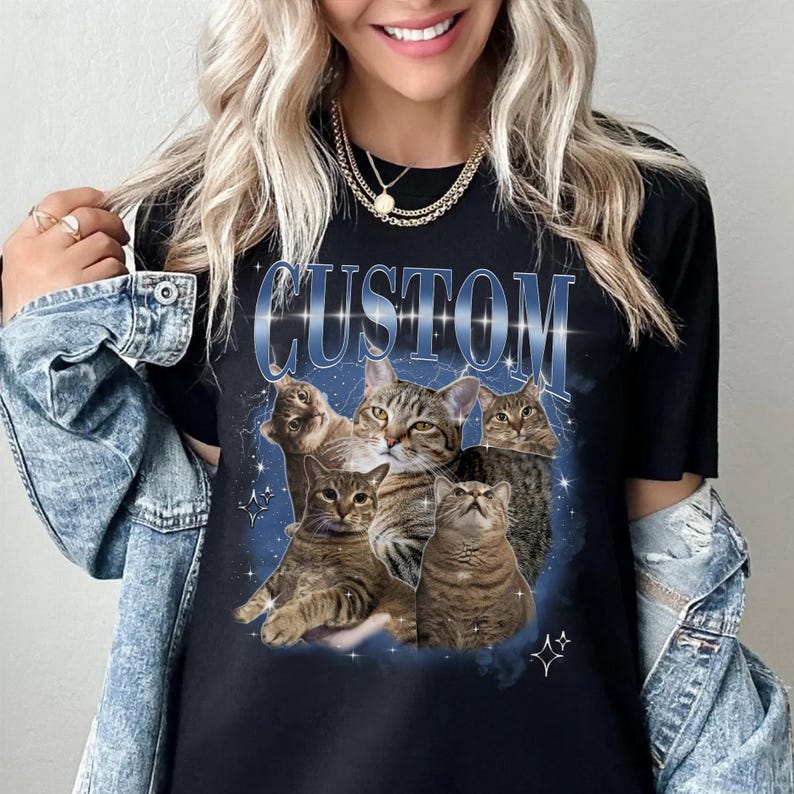 May include: Black t-shirt with a graphic of five cats in a galaxy print. The text "CUSTOM" is printed in blue with a glittery effect.