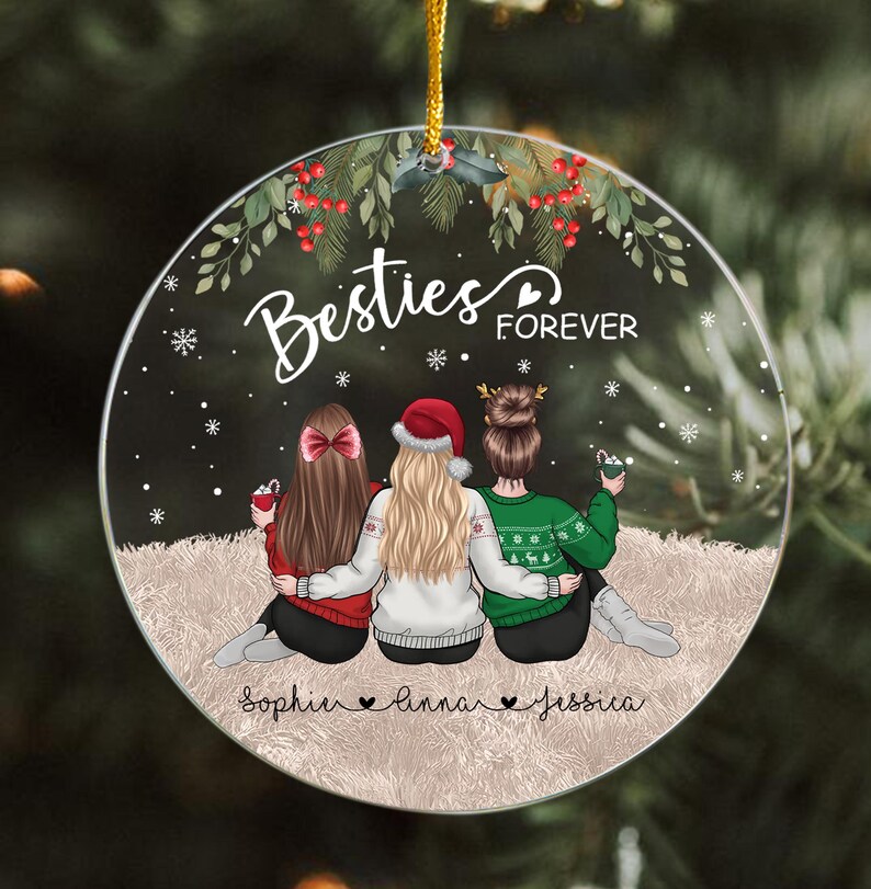 Pu&ograve; includere: Un ornamento natalizio rotondo con tre figure, ognuna con un'acconciatura diversa e che indossa un maglione rosso, un cappello da Babbo Natale e un maglione verde. L'ornamento recita "Besties Forever" con i nomi sotto.