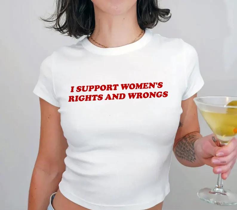 May include: White crop top with the red text "I SUPPORT WOMEN'S RIGHTS AND WRONGS". The shirt is a short-sleeved, fitted style. A martini glass with a green olive is in the background.