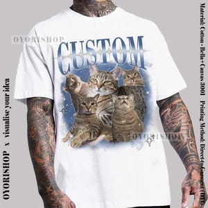May include: White t-shirt with a blue and white graphic of cats with the word "CUSTOM" printed in blue letters.