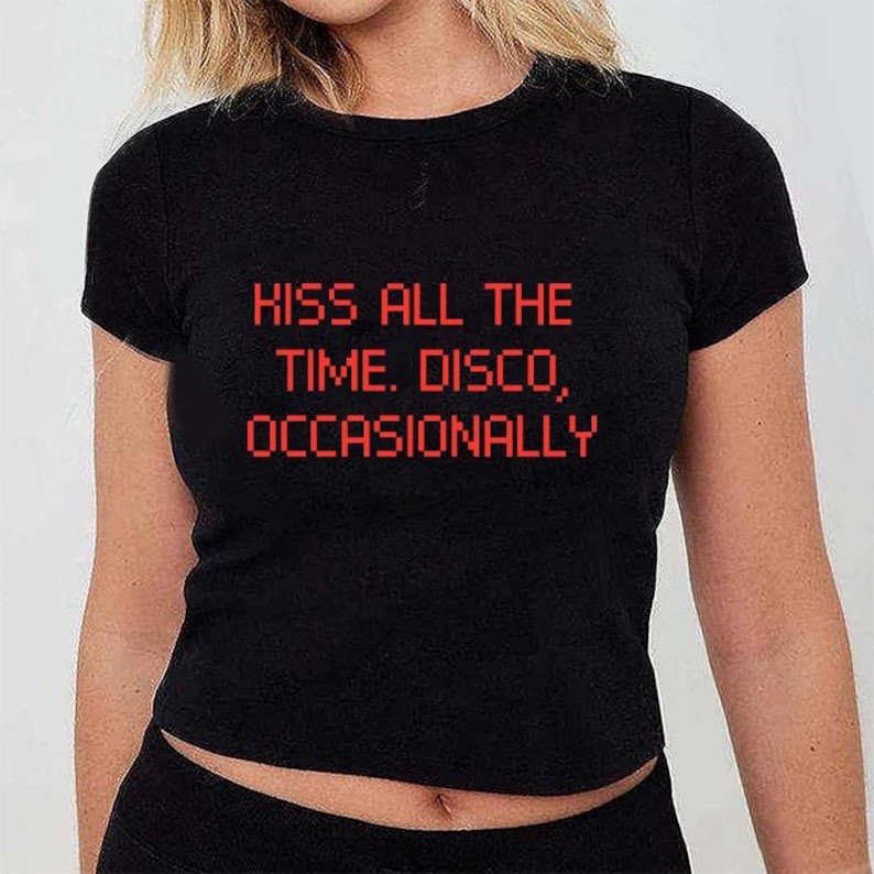 May include: Black t-shirt with the red text "KISS ALL THE TIME. DISCO, OCCASIONALLY." The shirt has a crew neck and short sleeves. The text is in a pixelated font.