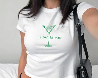 May include: White t-shirt with a green shamrock in a martini glass and the text "a tini bit irish"