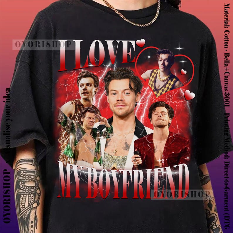 Op de afbeelding: Een zwart T-shirt met een grafische print van een groep mannen met de tekst "I Love My Boyfriend" in rood en wit. De grafiek is omringd door rode harten en bliksem.